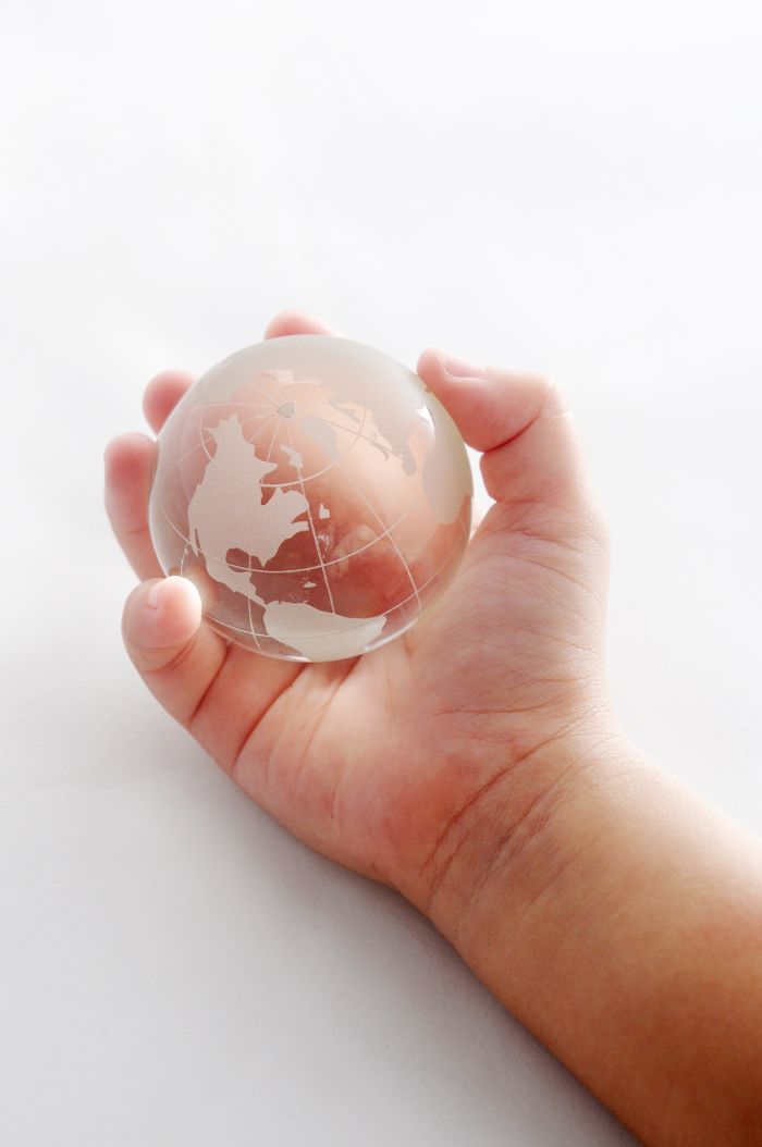 A child's hand holding a glass globe, symbolizing global unity and peace.