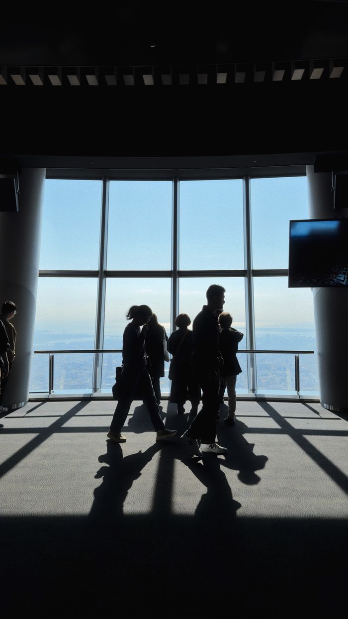 Visitors silhouetted against the panoramic view from Tokyo Skytree's observation deck.