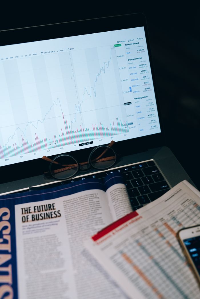 Close-up of laptop screen with business analytics, book, and eyeglasses.